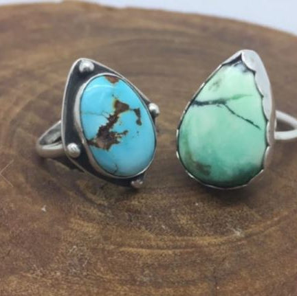 Green sea glass rings on a wooden stick with green leaves in the background